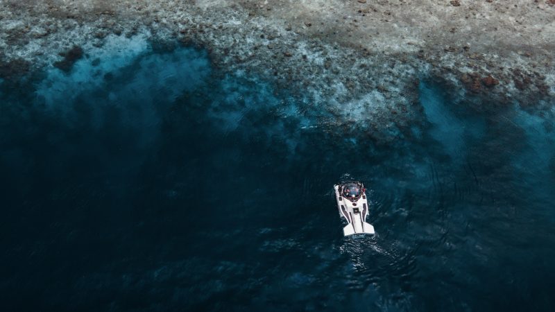 aerial view of a submersible at the surface of the ocean next to a reef in the maldives