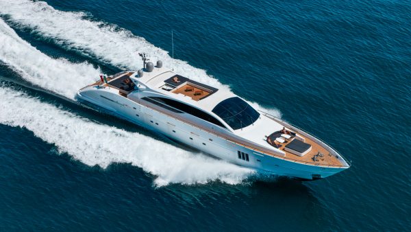 aerial view of a luxury yacht speeding across a calm blue ocean with people sunbathing