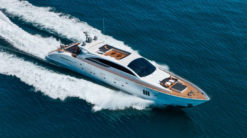 aerial view of a luxury yacht speeding across a calm blue ocean with people sunbathing