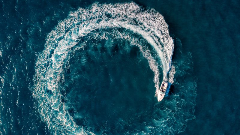 aerial view of a speedboat from the top with a circle of wake in a blue ocean