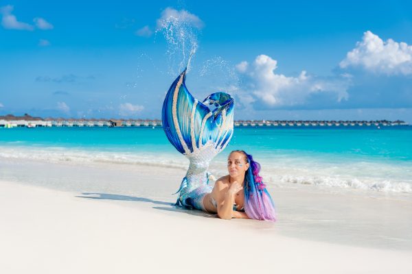 Making Waves: Mermaid Magic at Finolhu: a mermaid on the beach in finolhu in the maldives with tail in the air and water splashing