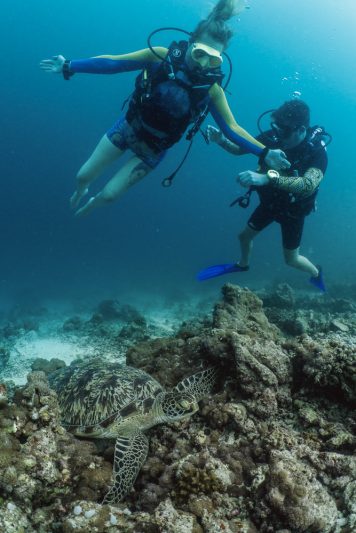 Sophie Morgan, Dive butler Ambassador, and founder Alexis Vincent underwater diving with a green sea turtle in the maldives