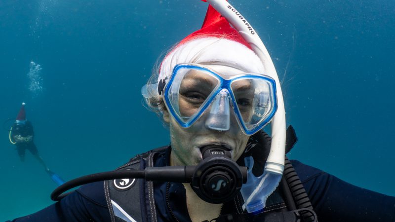 Close up of Sophie Morgan, Dive Butler Ambassador, underwater wearing scuba equipment and a santa hat